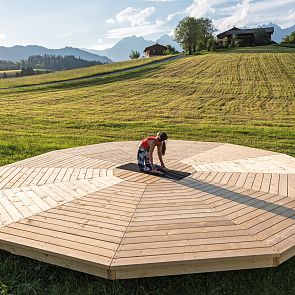 Frau macht Yoga auf der Yogaplattform inmitten der Natur in Kitzbühel