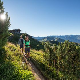 Paar bei einer Wanderung in den Kitzbüheler Alpen mit blauem Himmel und Sonnenschein